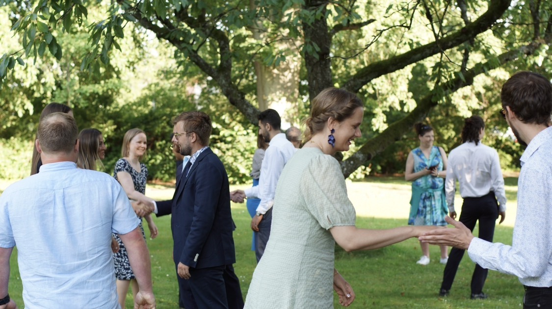 Somriga, finklädda glada personer som lär sig att dansa på en grön gräsmatta.